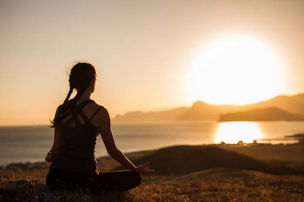 Vrouw doet yoga op de natuur buiten bij zonsopgang