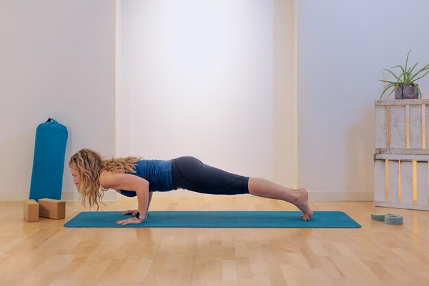 Vrouw doet yoga plank positie op de mat in een studio