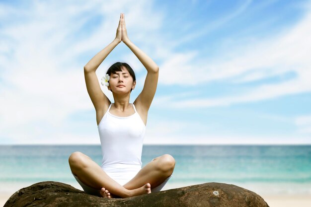 Foto vrouw doet yoga tegen zee en lucht.