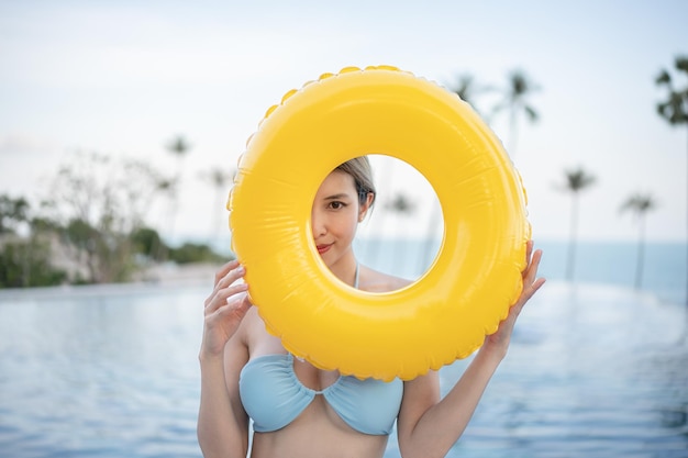 Vrouw draagt blauwe zwembroek poseren met gele opblaasbare rubberen ring.