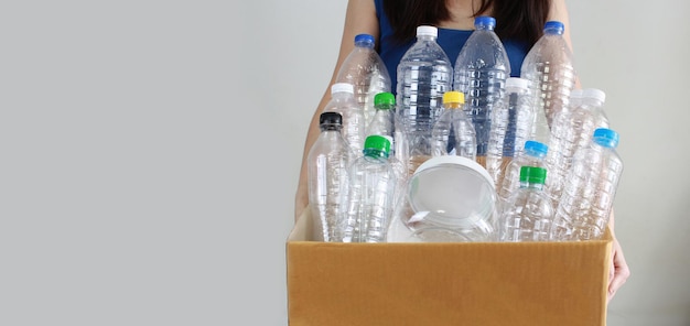 Vrouw draagt een gerecyclede plastic fles die in een kartonnen doos zit voor duurzaamheid en milieu. A Bespaar energie en wereld.