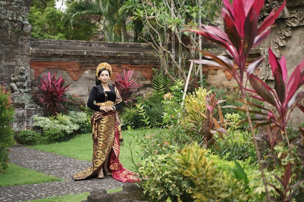 Vrouw draagt een geweven sarong in een traditionele Balinese tuin