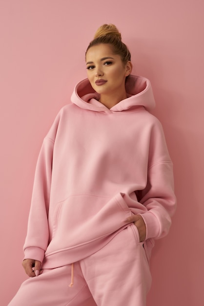 Foto vrouw draagt een roze sport-hoodie op een roze achtergrond