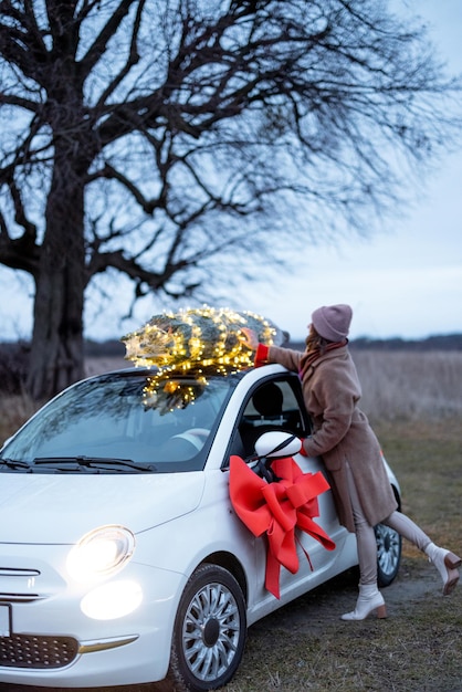 Vrouw draagt kerstboom met auto