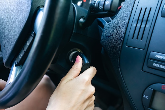 Vrouw draait contactsleutel in de auto. Meisje rijdt.