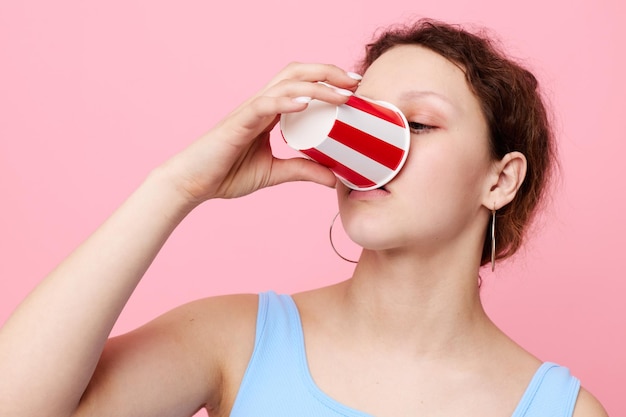 Vrouw drinken uit een wegwerpglas close-up roze achtergrond ongewijzigd