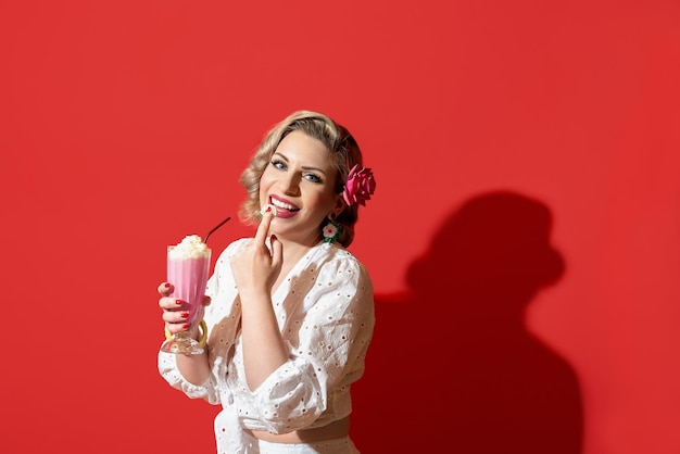Vrouw drinken van een milkshake tegen een rode achtergrond Retro-stijl vrouw portret