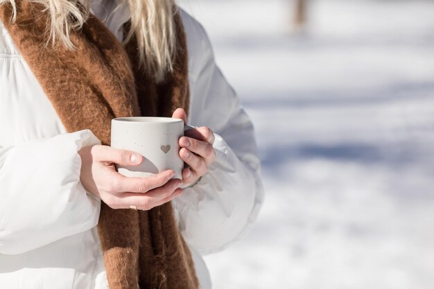 Vrouw drinkt een kop warme thee of koffie buiten in het zonlicht op een koude winterdag Valentijnsdag