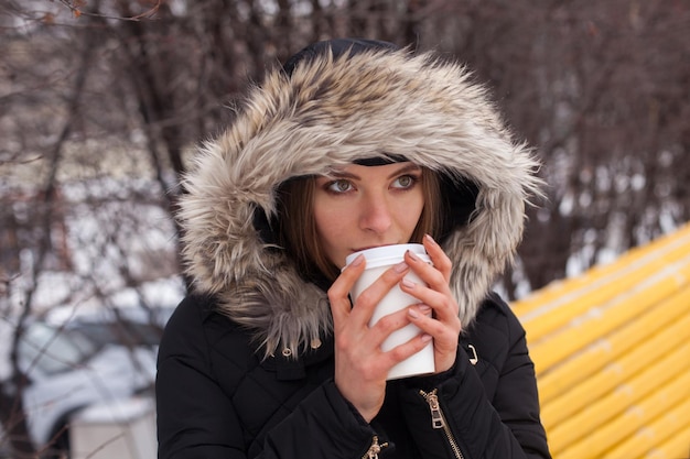 Vrouw drinkt haar warme drank thee of koffie uit beker Winterseizoen