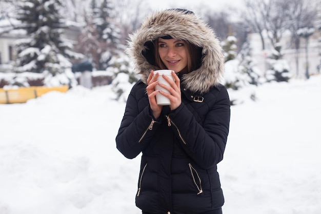 Vrouw drinkt haar warme drank thee of koffie uit beker winterseizoen