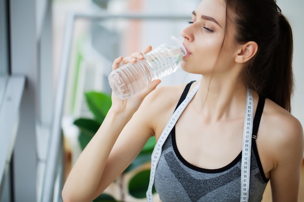 Vrouw drinkwater in de sportschool na het sporten.