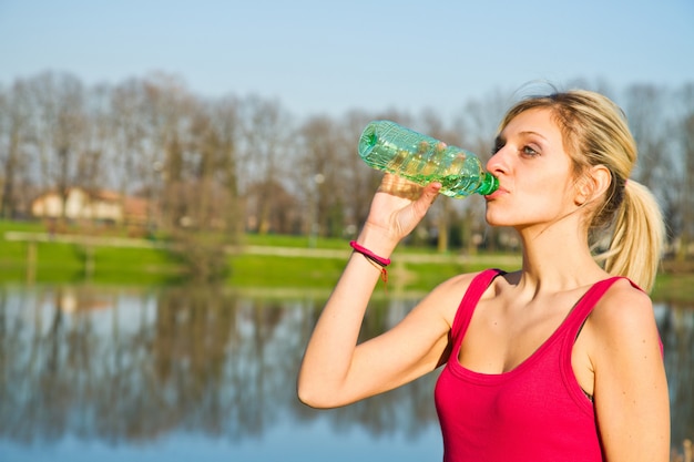 Vrouw drinkwater uit de fles na fitness sport oefening