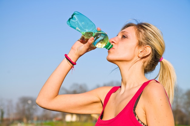 Vrouw drinkwater uit de fles na fitness sport oefening