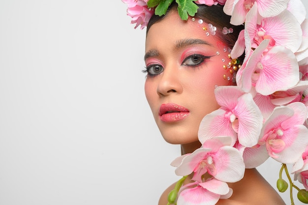 Vrouw droeg roze make-up en versierde prachtig de bloemen geïsoleerd op wit