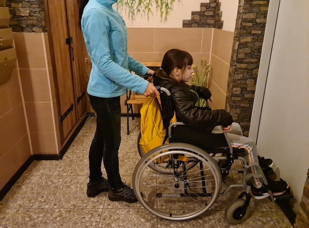 Foto vrouw duwt gehandicapte zus in rolstoel en de deur van de moderne lift gaat open