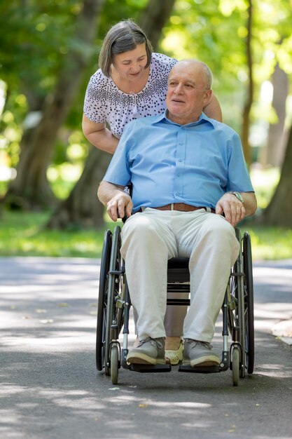 Vrouw duwt man in rolstoel in park