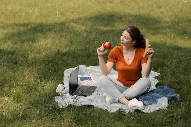 Vrouw eet appel en banaan in park