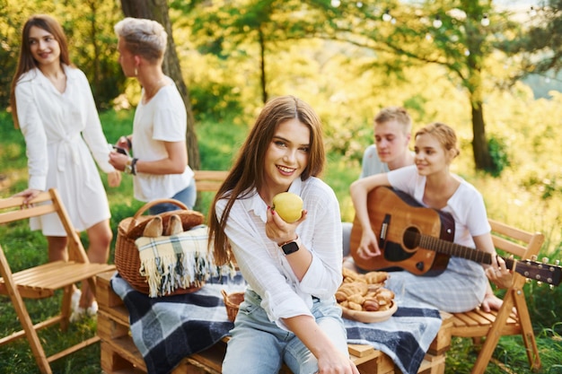 Vrouw eet appel groep jongeren hebben vakantie buiten in het bos conceptie van weekend en vriendschap