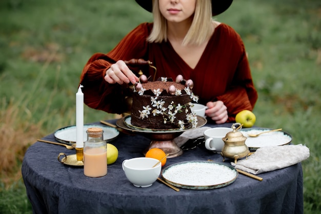 Vrouw eet een chocoladetaart in een tuin