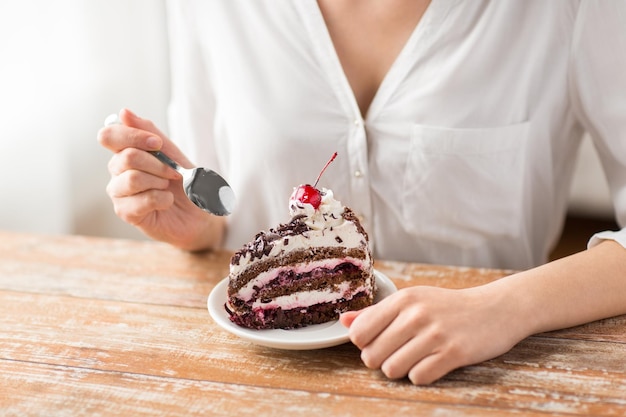 Vrouw eet een stuk laag taart met kersen