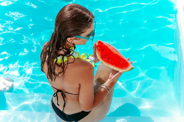 Vrouw eet een watermeloen bij het zwembad