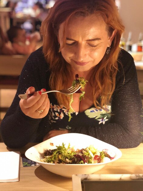 Foto vrouw eet eten op tafel in een restaurant