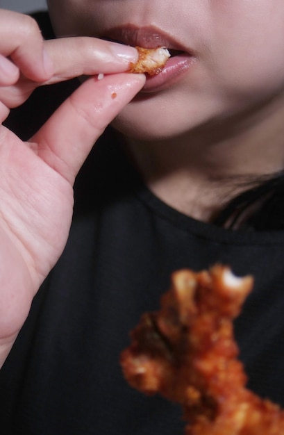 Vrouw eet gebakken kip Straatvoedsel