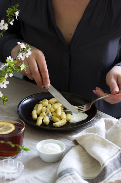 Vrouw eet gestremde gnocchi. Ontbijttafel met gnocchi en thee.