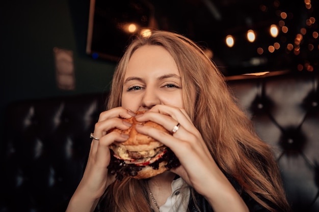 Vrouw eet hamburger in café