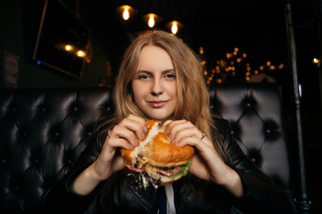 Vrouw eet hamburger in café