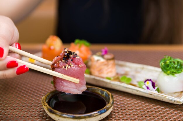 Vrouw eet heerlijke gunkan sushi close-up op eetstokjes