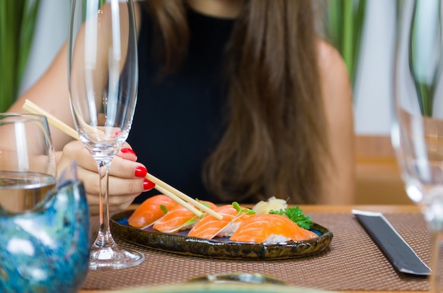 Vrouw eet heerlijke sushi close-up op eetstokjes