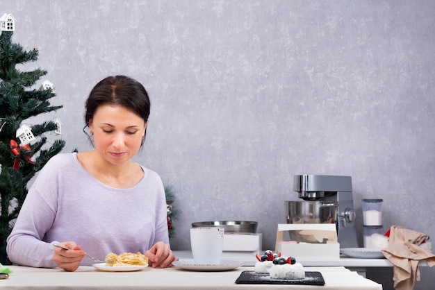 Vrouw eet in haar keuken. Ontbijt met dessert. Vakantie.