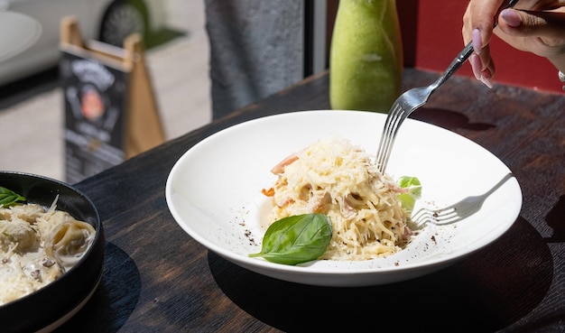 Vrouw eet Italiaanse pasta zittend aan de balie van het café en kijkt naar het raam tijdens de lunch