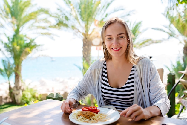 Vrouw eet pasta op de achtergrond van de zee