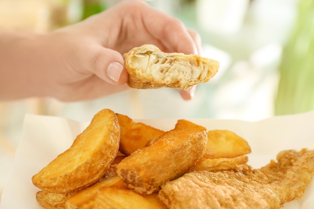 Vrouw eet smakelijke gebakken fish and chips close-up