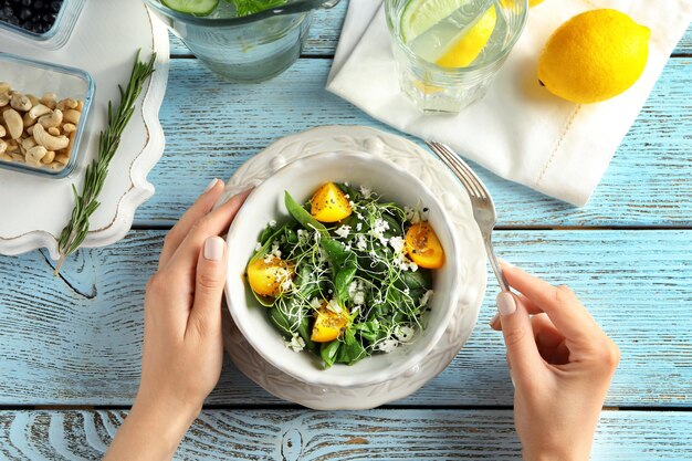 Vrouw eet superfood salade met tomaten en spinazie aan tafel