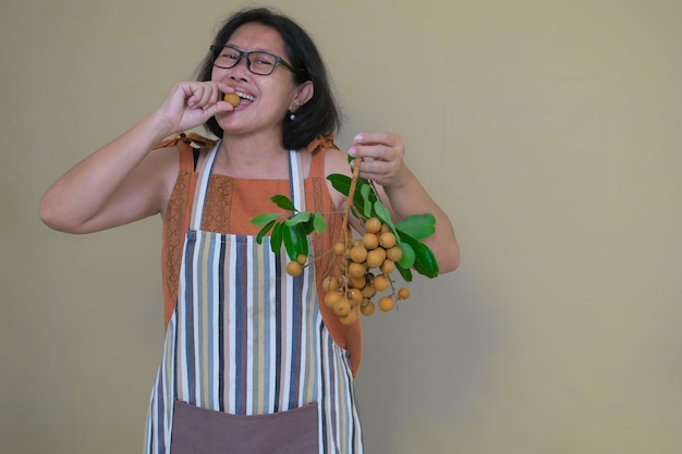 Vrouw eet verse longans en houdt een bosje in de linkerhand