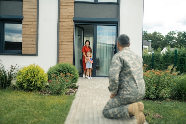 Vrouw en dochter. Vrouw en dochter voelen zich gelukkig als ze kijken naar de militaire dienaar die eindelijk thuiskomt