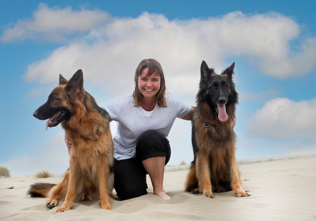 Vrouw en Duitse herders blijven op het strand