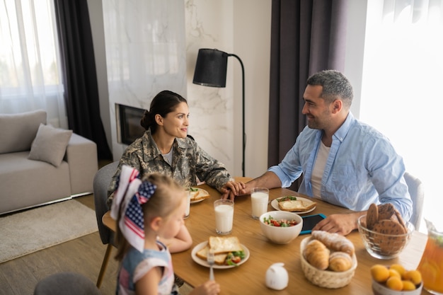 Vrouw en echtgenoot. Militaire vrouw die de hand van de man aanraakt tijdens het ontbijt met het gezin