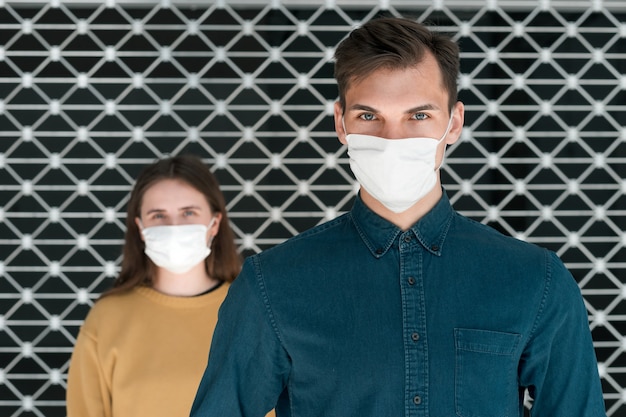 Vrouw en een man met beschermende maskers staan op afstand. concept van gezondheidsbescherming