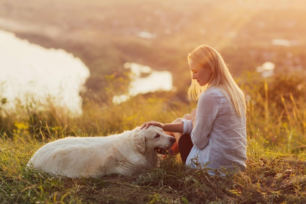 vrouw en golden retrieverhond op de heuvel op groen gras