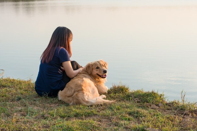 Vrouw en gouden hond op rivieroever