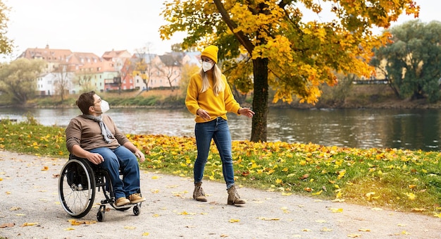 Foto vrouw en haar gehandicapte vriend in rolstoel, dragen ffp2 tijdens covid-19 pandemie