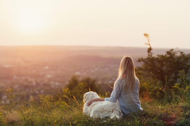 Vrouw en haar hond zitten en genieten van de zomerzonsondergang