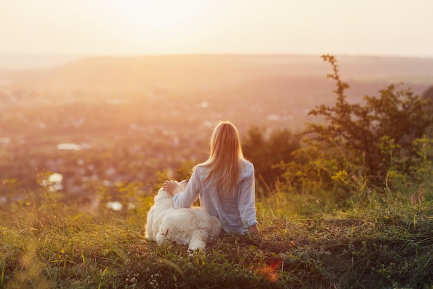 vrouw en haar hond zittend op de heuvel op het platteland