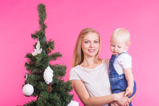 Vrouw en haar kind poseren naast de kerstboom