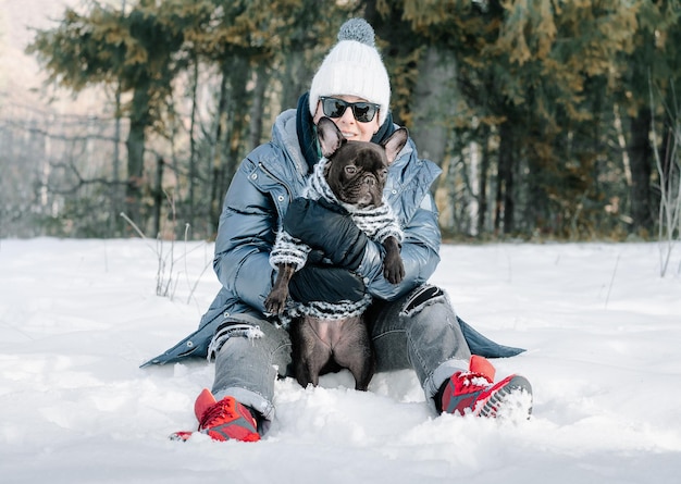 Vrouw en hond zitten in de sneeuw.
