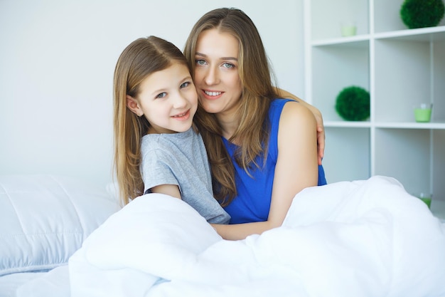 Vrouw en jong meisje liggend in bed glimlachen.